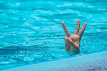 a person making a peace sign in a pool