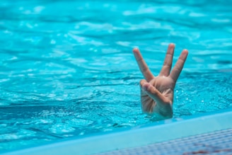 a person making a peace sign in a pool