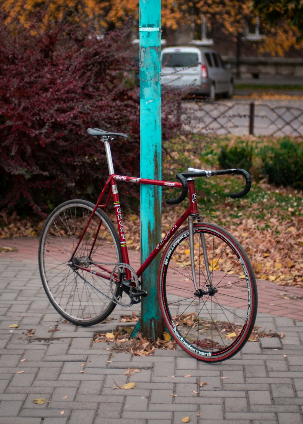 a red bicycle is chained to a blue pole