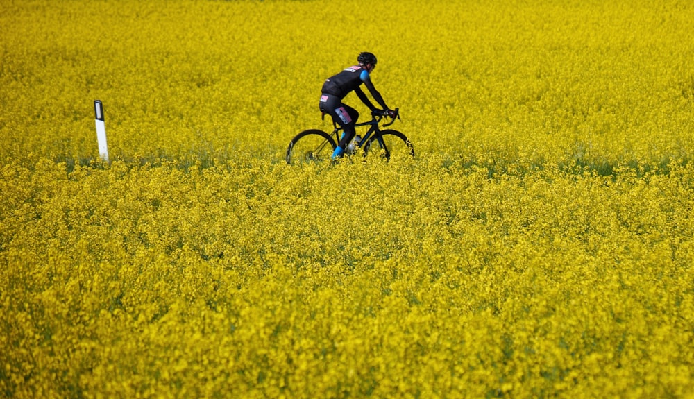 a man riding a bike through a field of yellow flowers
