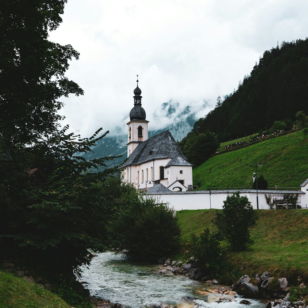a river running through a lush green hillside next to a church