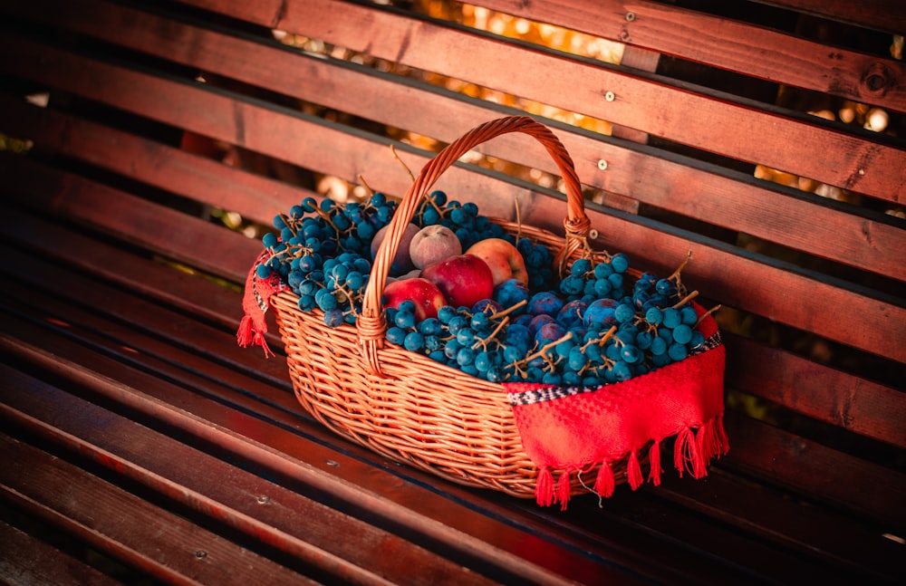 a basket filled with fruit sitting on top of a wooden bench