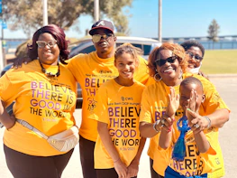 A group photo of the foundation’s team smiling warmly in deep green and orange attire.