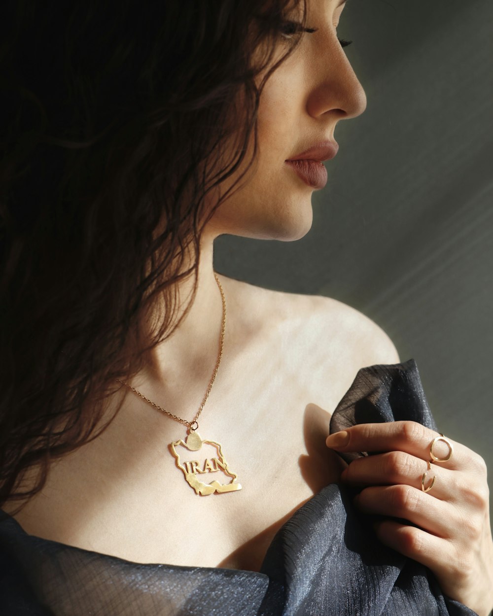 a woman in a black dress holding a gold necklace
