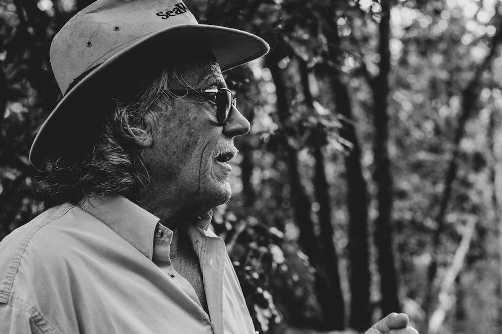 a man wearing a hat and glasses in the woods