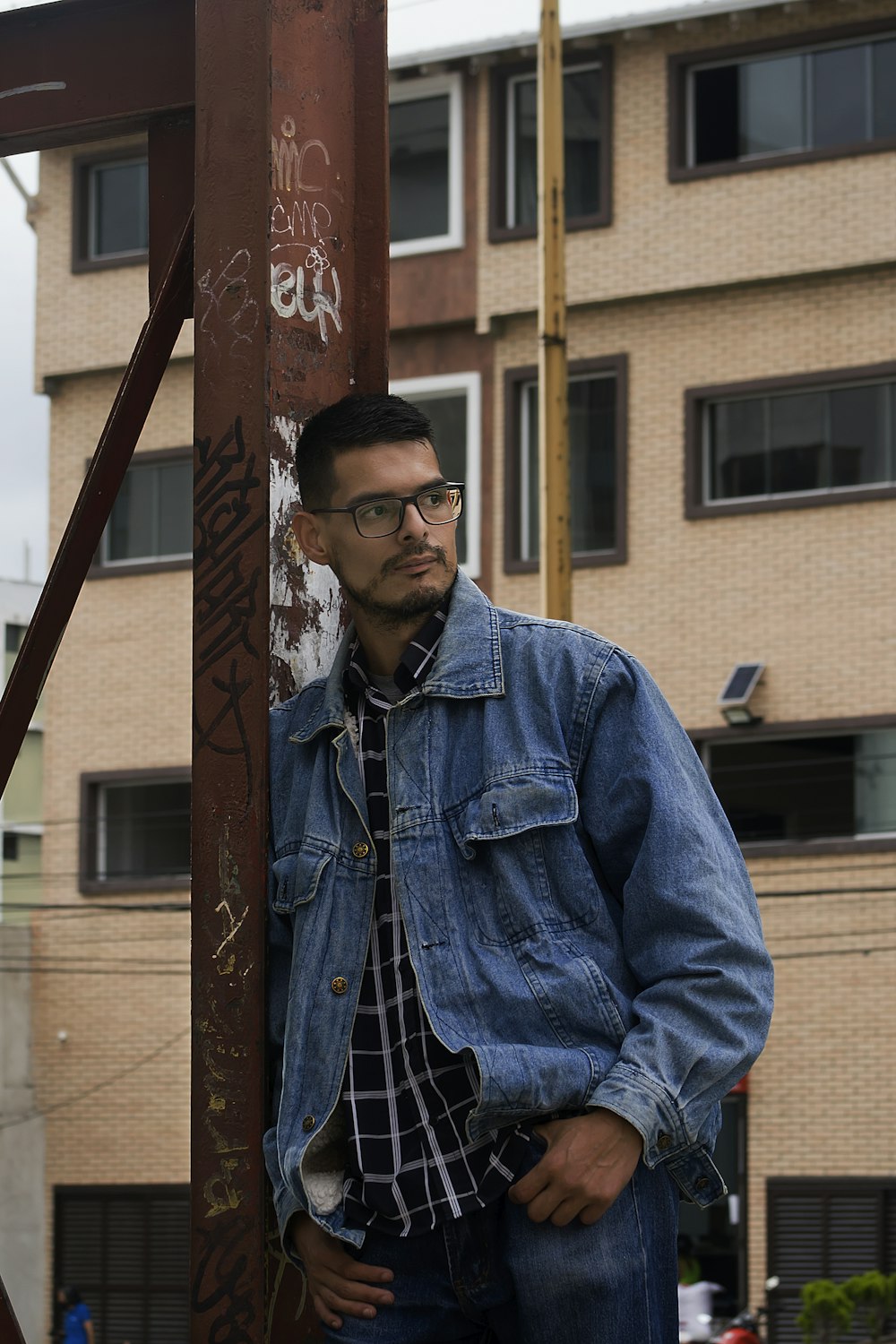 a man leaning against a pole with graffiti on it