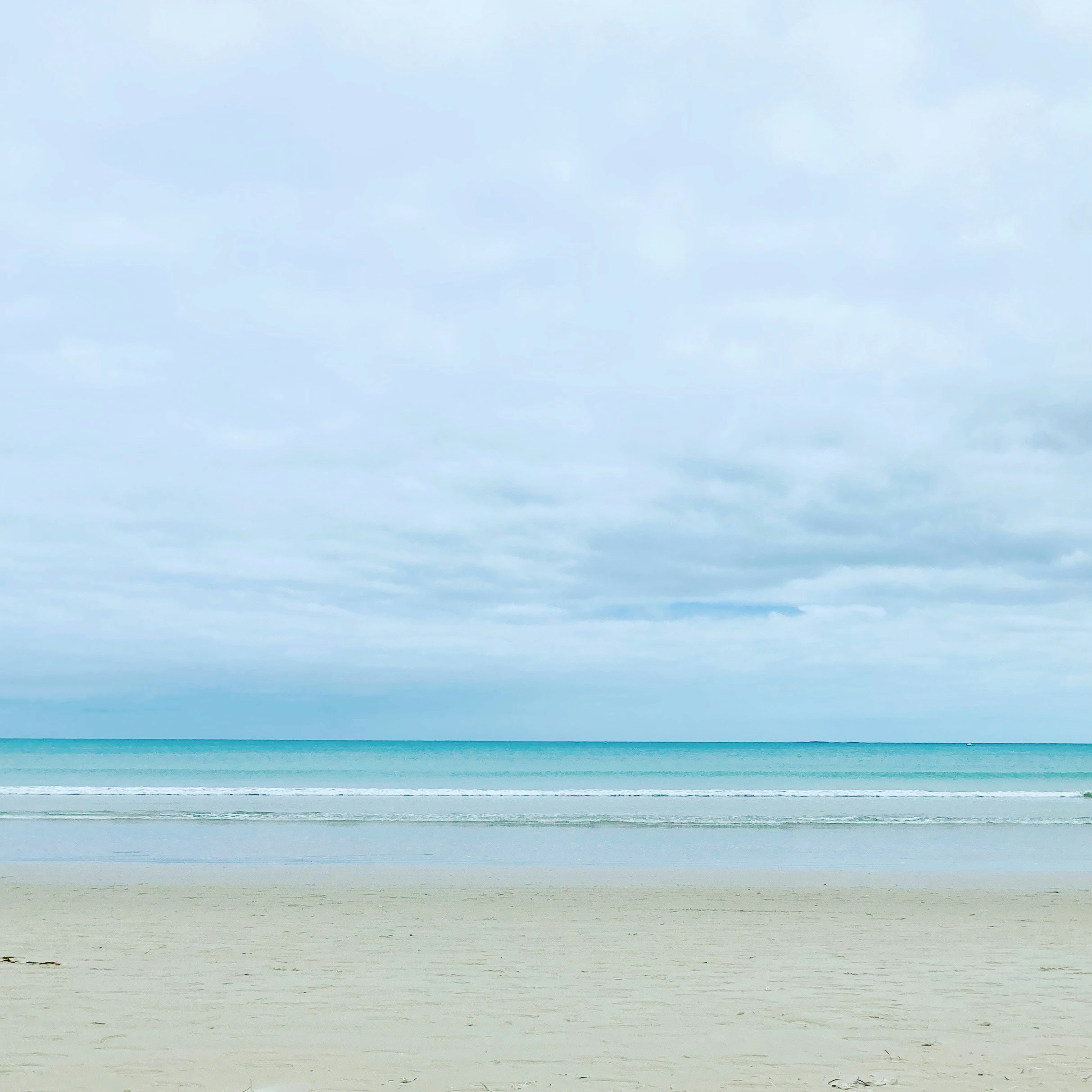 a person walking on a beach carrying a surfboard