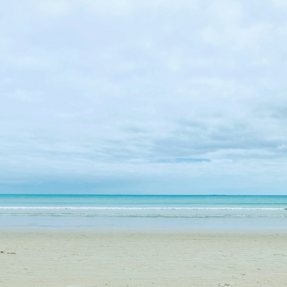 a person walking on a beach carrying a surfboard