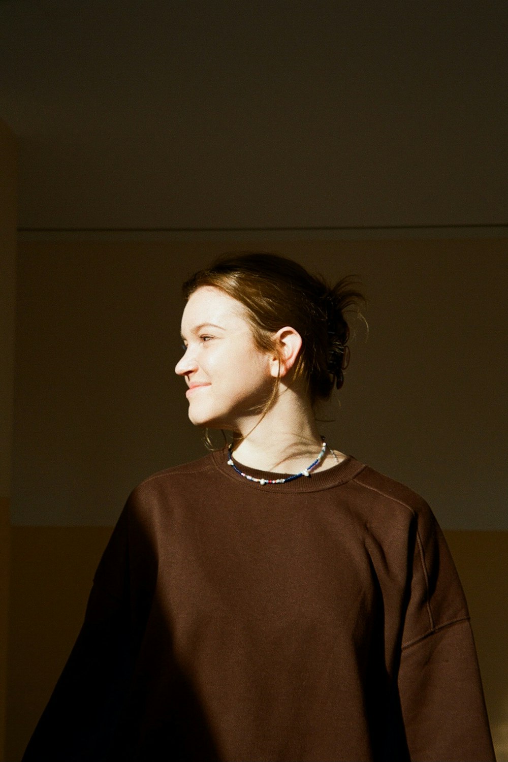 a woman standing in a room with her hair in a bun