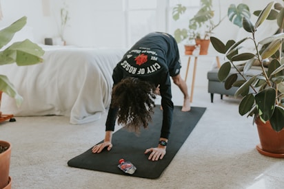 Woman practicing yoga on a mat in a cozy home environment with plants.