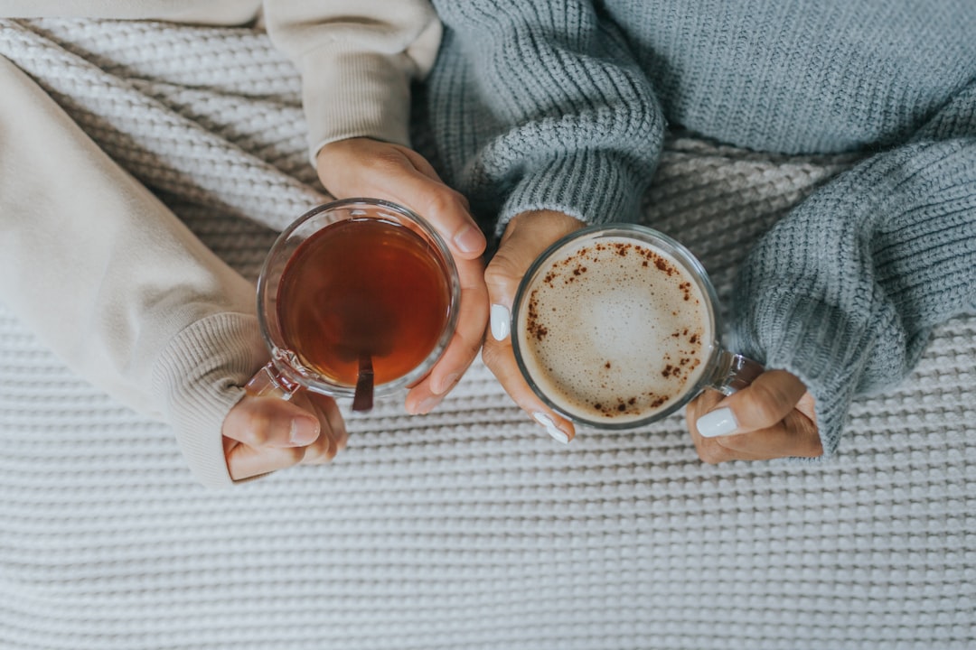 a person holding a doughnut, Tea and coffee in bed.