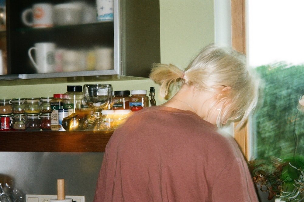 a woman standing in a kitchen next to a window