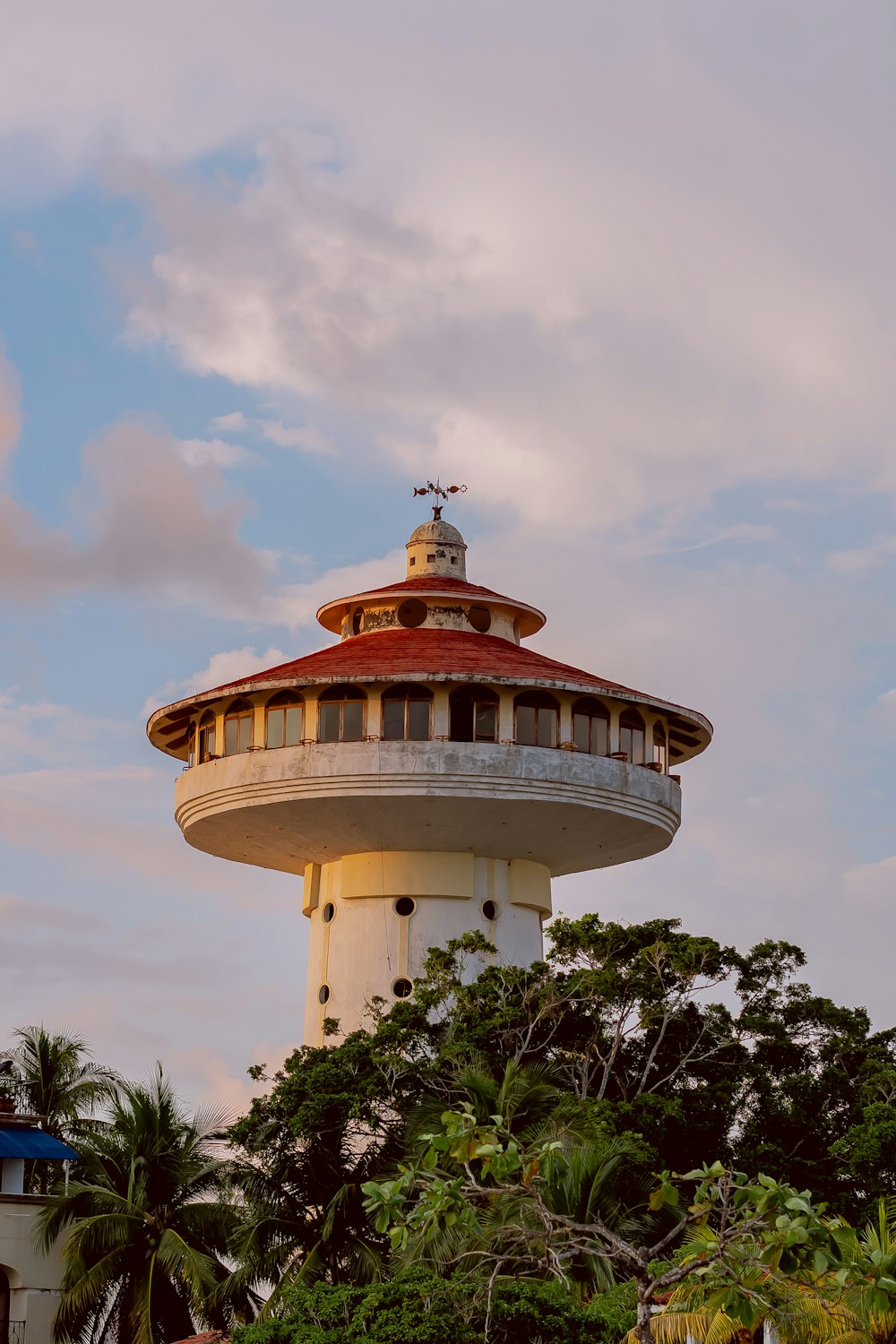 a white tower with a red roof surrounded by trees