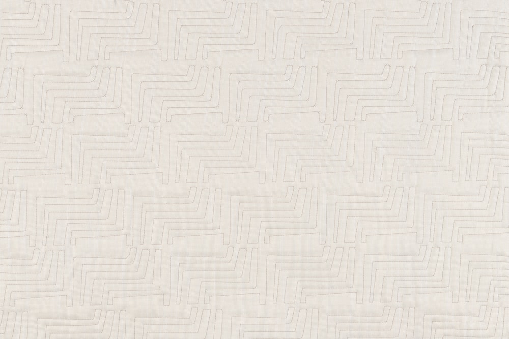 a close up of a white quilt with a pattern on it