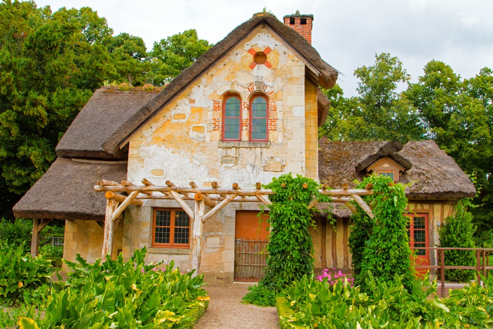 a house with a thatched roof surrounded by greenery