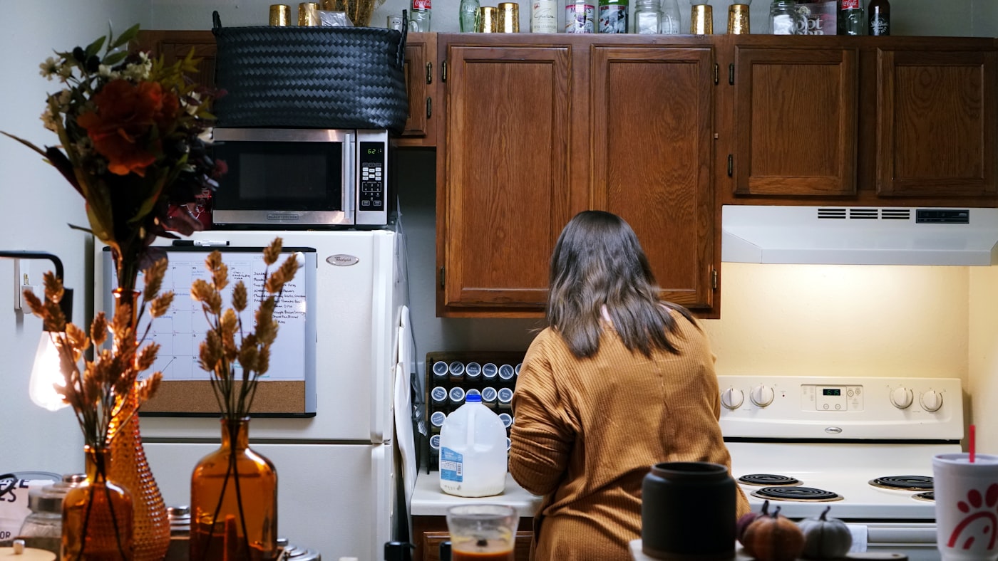Small apartment kitchen with warm amber glass vases, brown wood cabinets, and dried autumn flowers