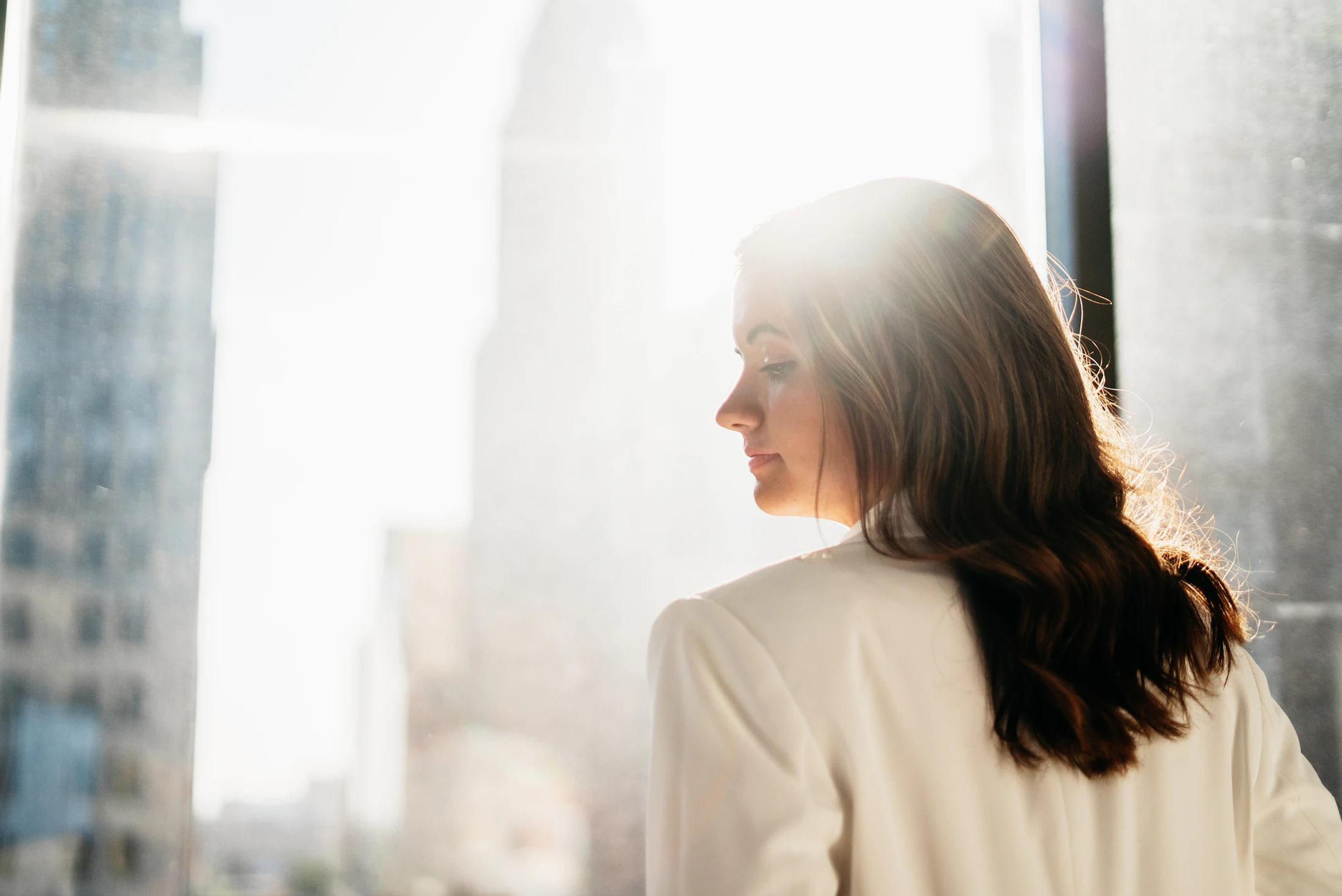 A person in profile looking out a window, quiet and thoughtful