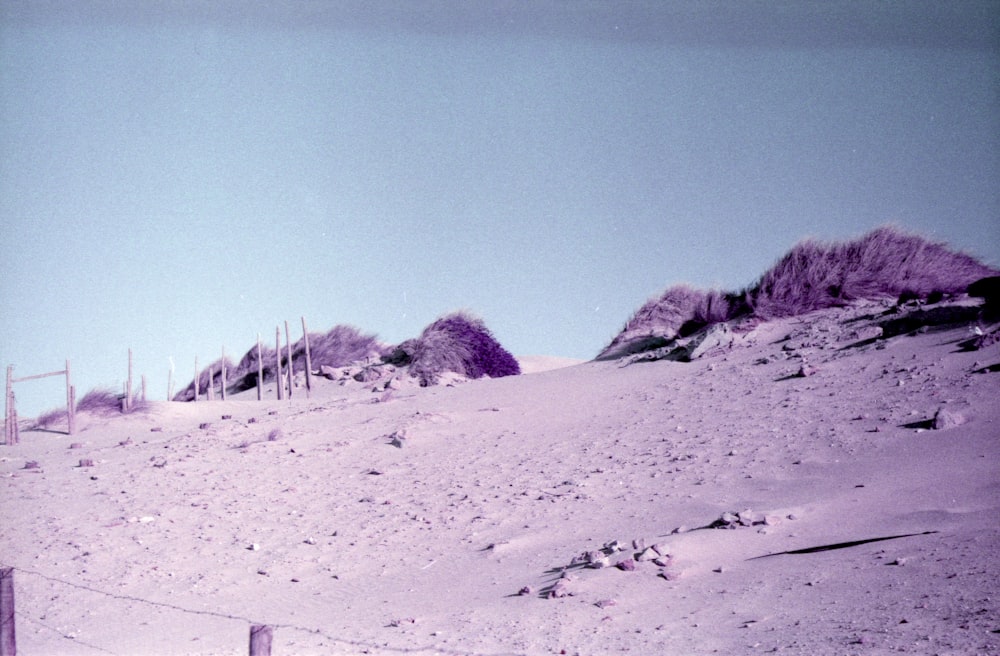 ein schneebedeckter Hügel mit einem Zaun im Vordergrund