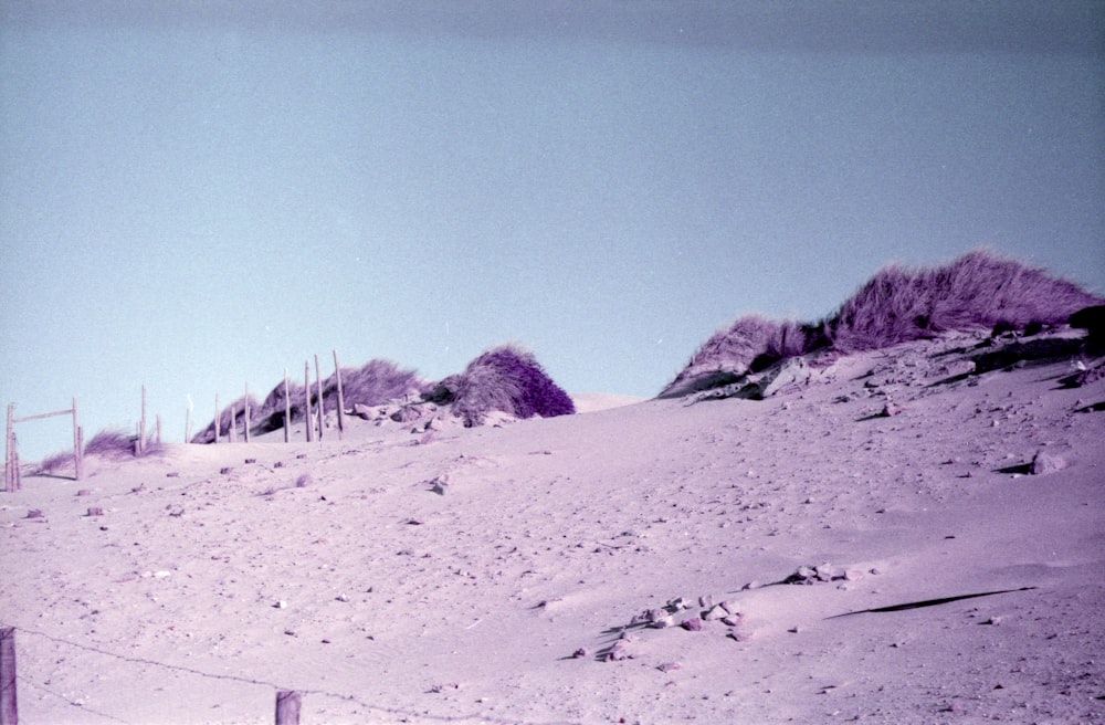 a snow covered hill with a fence in the foreground