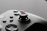 A close-up view of a video game controller with several buttons and a joystick, showcasing a sleek and modern design.