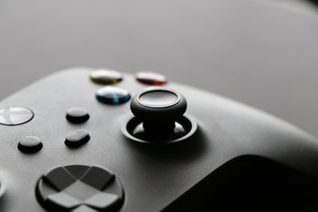 Close-up of a sleek, modern game controller resting on a colorful game-themed desk.