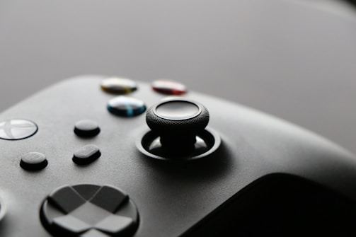 A close-up view of a video game controller with several buttons and a joystick, showcasing a sleek and modern design.
