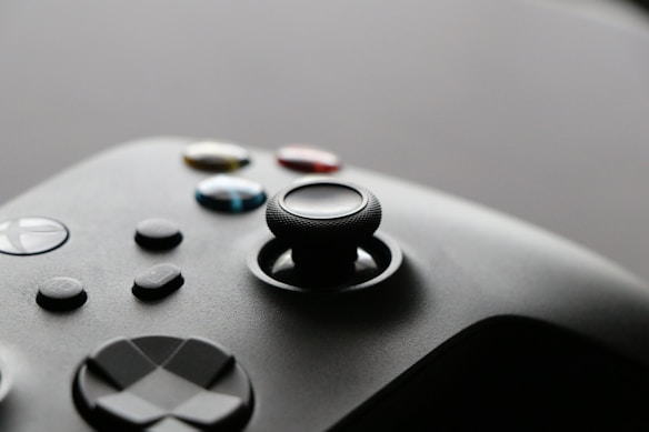 A close-up view of a video game controller with several buttons and a joystick, showcasing a sleek and modern design.