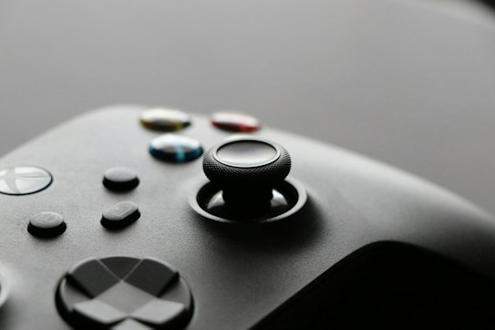 A close-up view of a video game controller with several buttons and a joystick, showcasing a sleek and modern design.