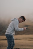 a man standing in a field holding a cell phone