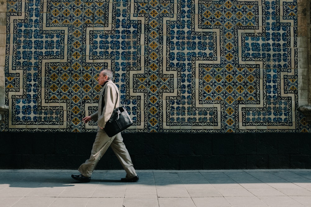 a man walking down a sidewalk next to a building