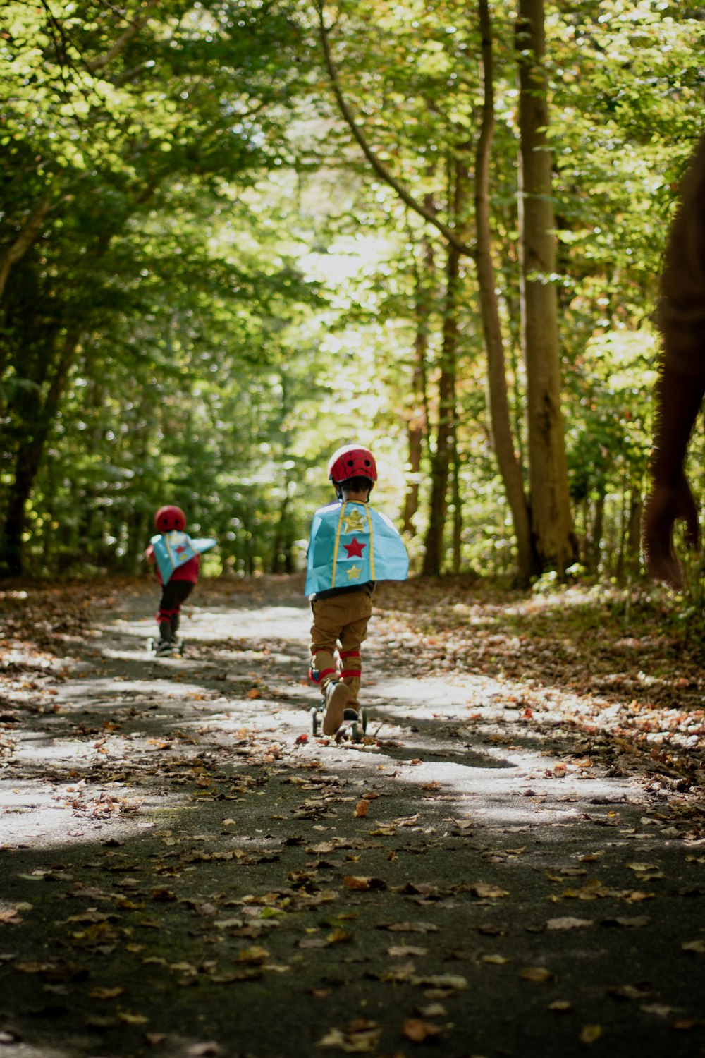 a couple of kids riding bikes down a dirt road