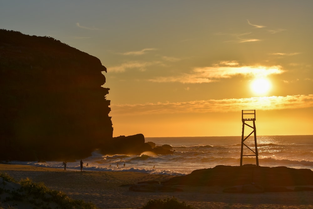 the sun is setting over the ocean with a tower in the foreground