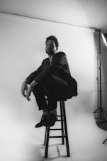 a man sitting on a stool in a photo studio