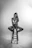 a black and white photo of a woman sitting on a stool