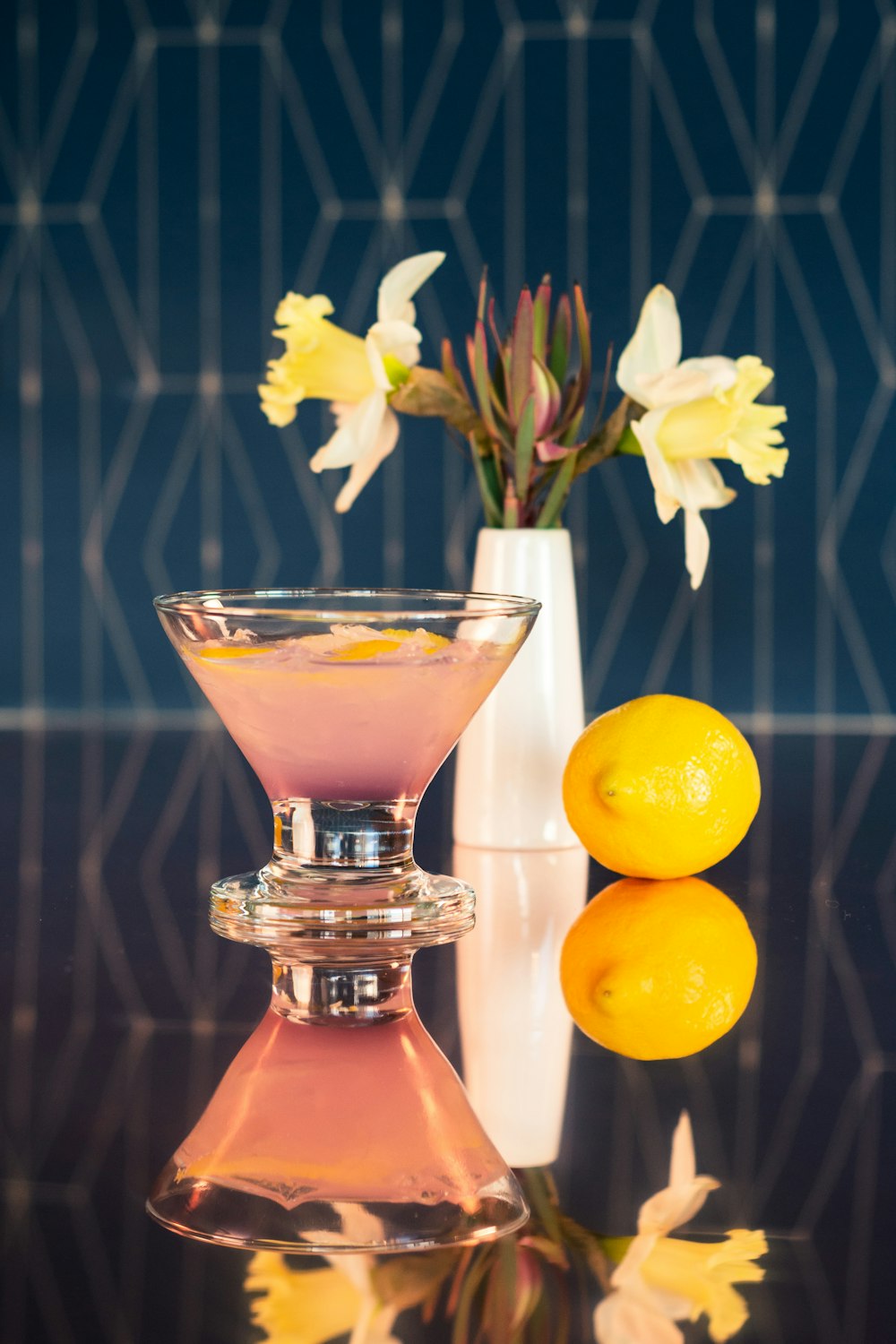 a vase with flowers and two lemons on a table