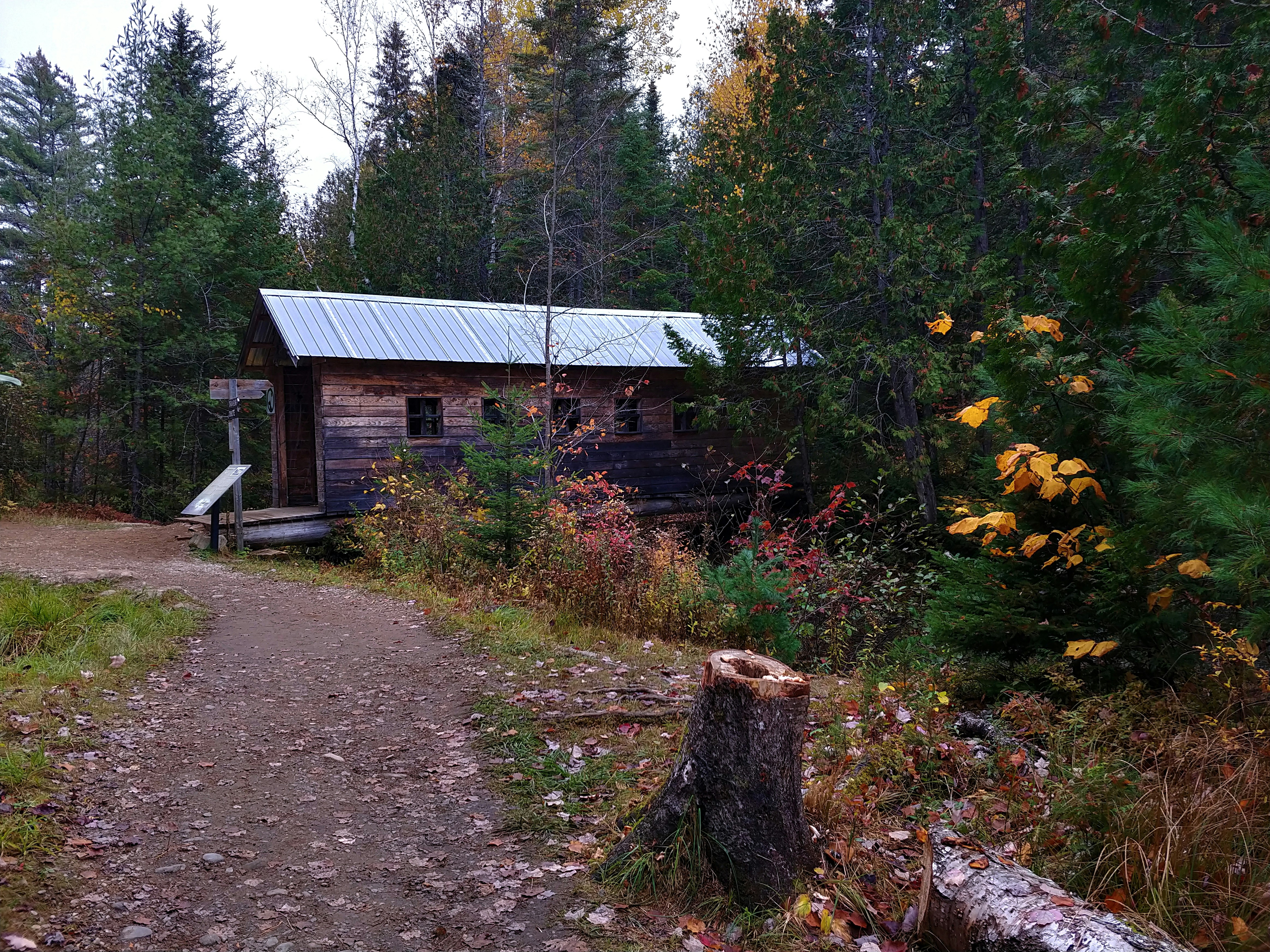 a small cabin in the woods near a trail