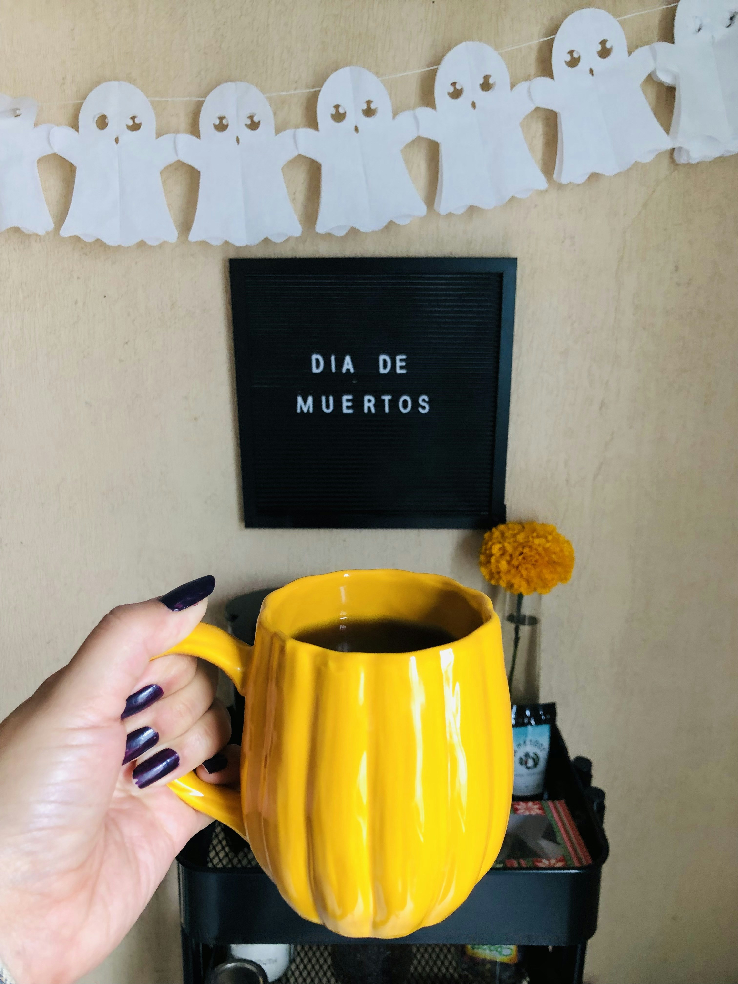 une personne tenant une tasse jaune dans sa main