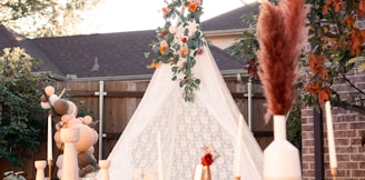 a teepee with flowers and candles in front of a house