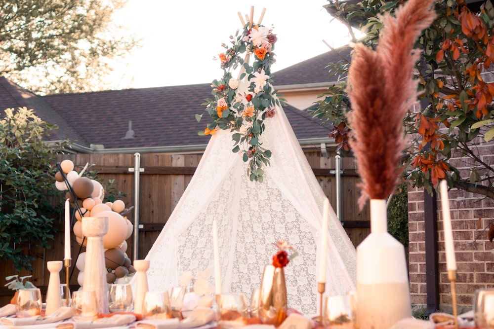 a teepee with flowers and candles in front of a house
