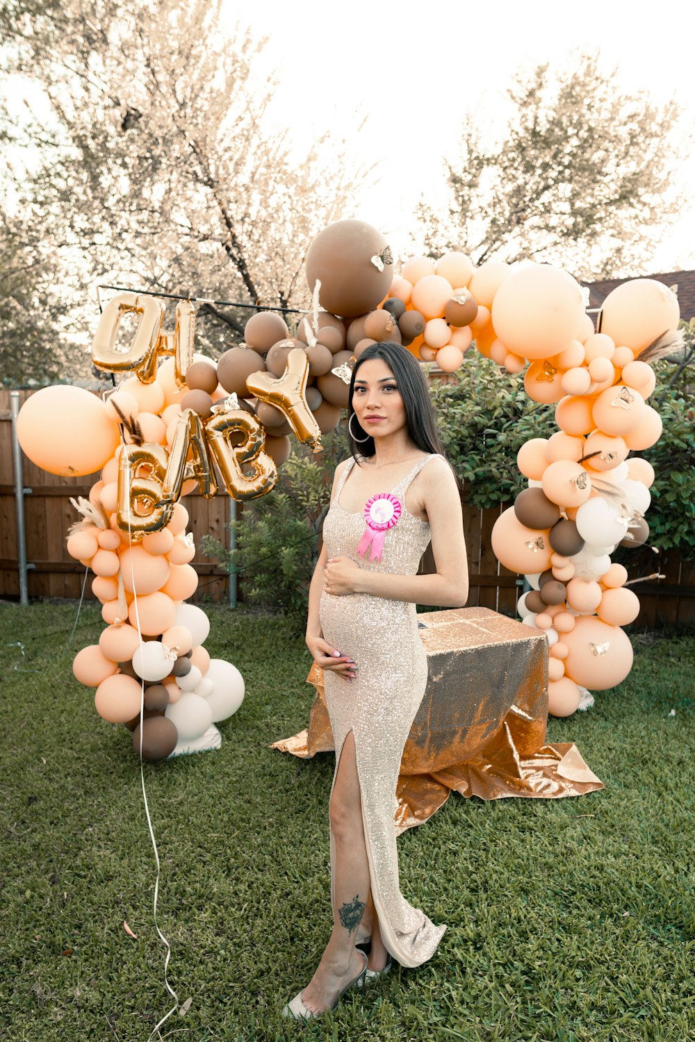 a pregnant woman standing in front of a balloon arch