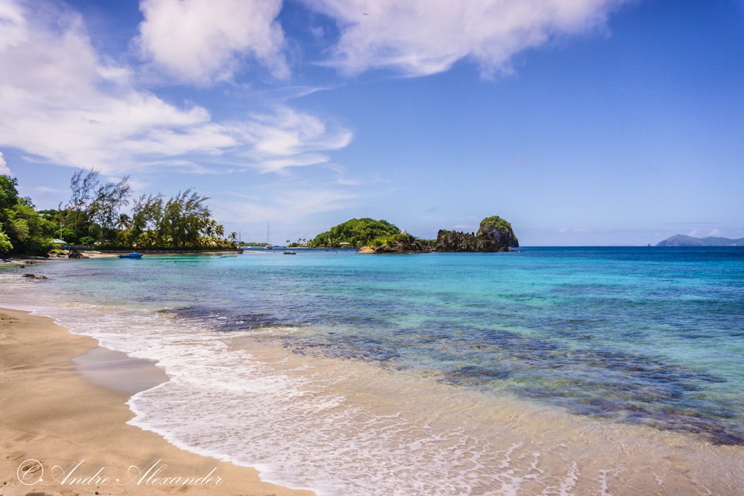 a sandy beach with clear blue water and a small island in the distance