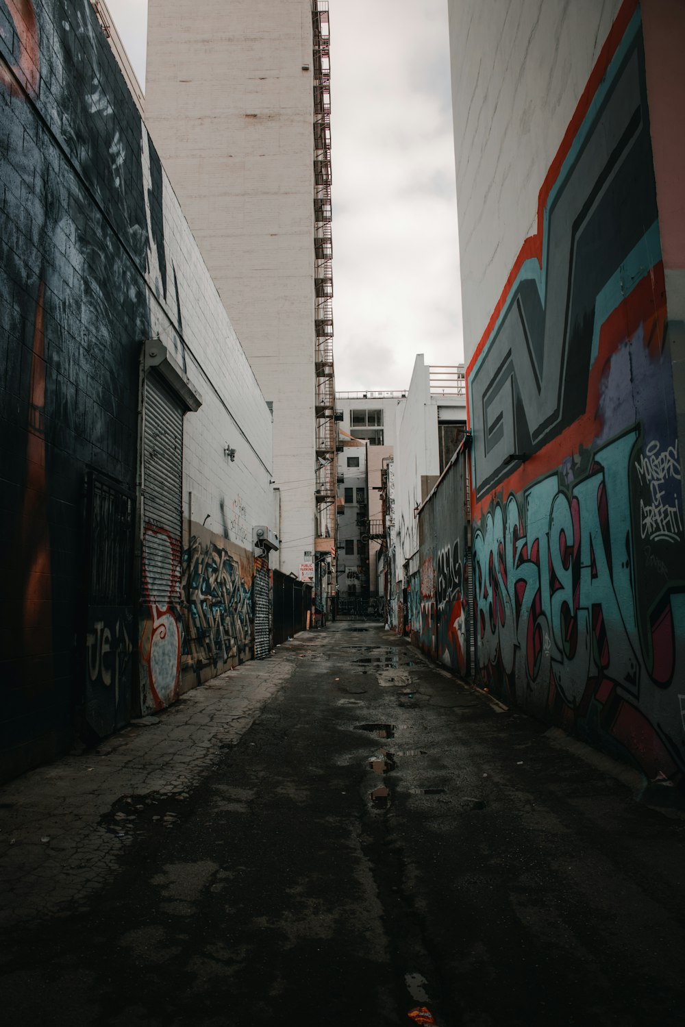 a narrow alley with graffiti on the walls