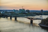 A sleek steel bridge under construction with workers inspecting beams at sunset.