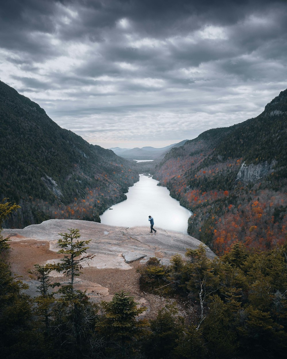 uma pessoa em pé no topo de uma montanha com vista para um lago