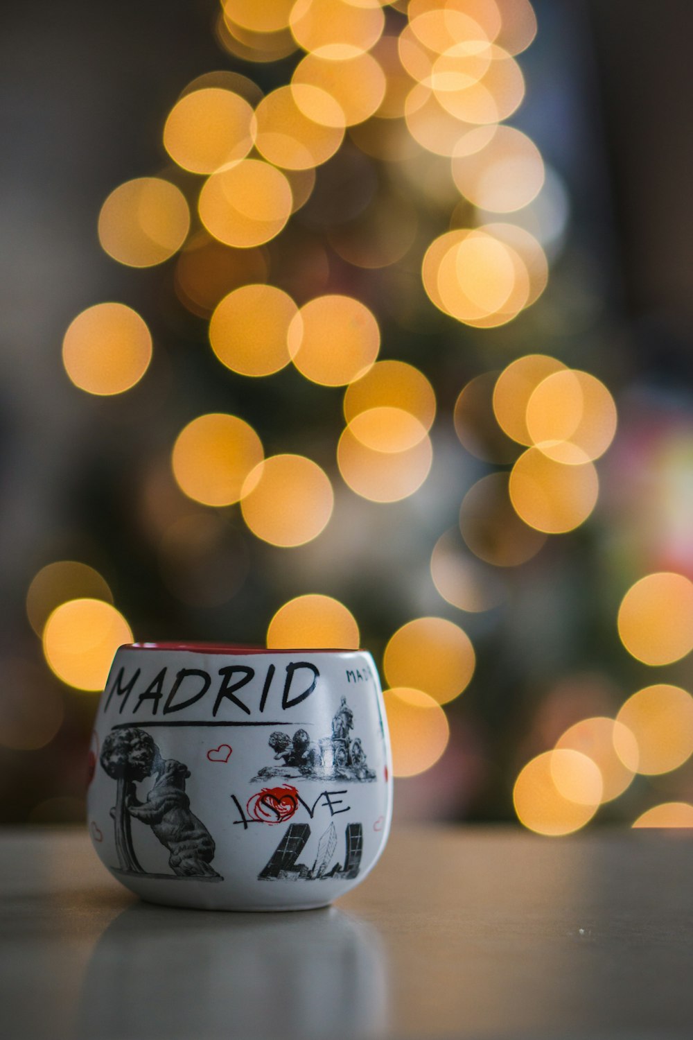 a coffee cup sitting on a table in front of a christmas tree