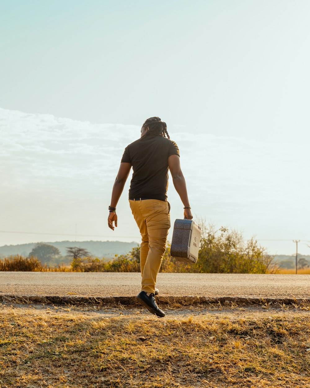 a man walking down a road carrying a suitcase