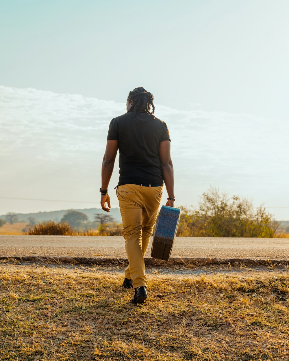 a man walking down a road carrying a suitcase