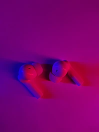 A pair of modern wireless earbuds glowing softly against a dark background.