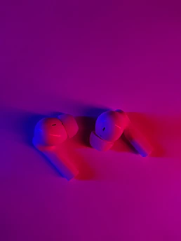 Trendy wireless earbuds glowing softly against a vibrant background.