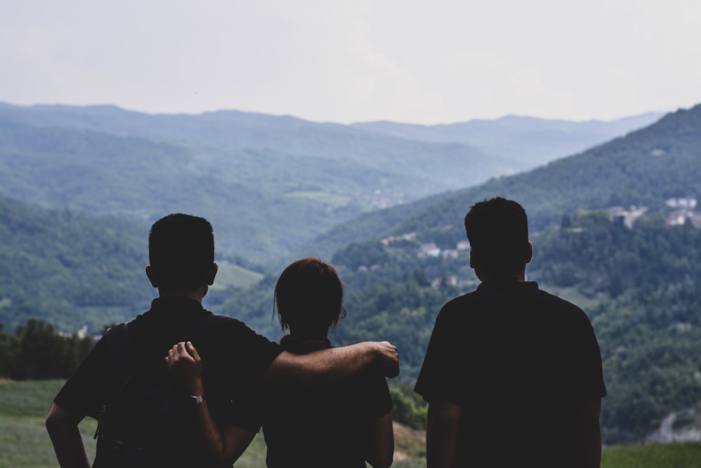 a group of people standing on top of a lush green hillside